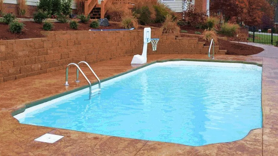 The Dominican pool beside a stone wall, with a ladder on the near side and a basketball hoop at the far end.